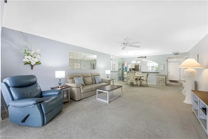Living area with ornamental molding, carpet floors, a chandelier, and a ceiling fan