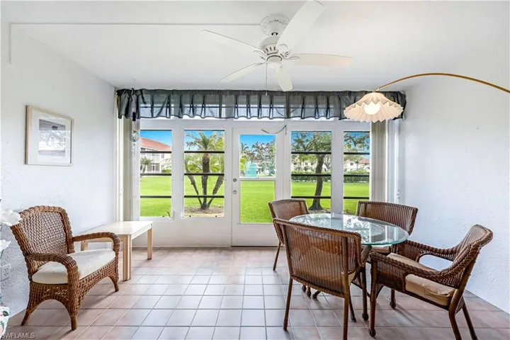 Sunroom / solarium featuring ceiling fan, tile patterned flooring, outdoor dining space, a textured wall, and french doors
