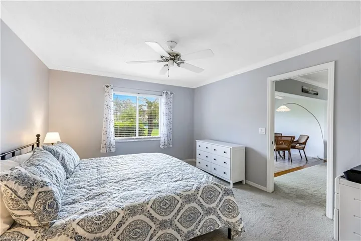 Bedroom with light colored carpet, crown molding, a textured ceiling, and ceiling fan