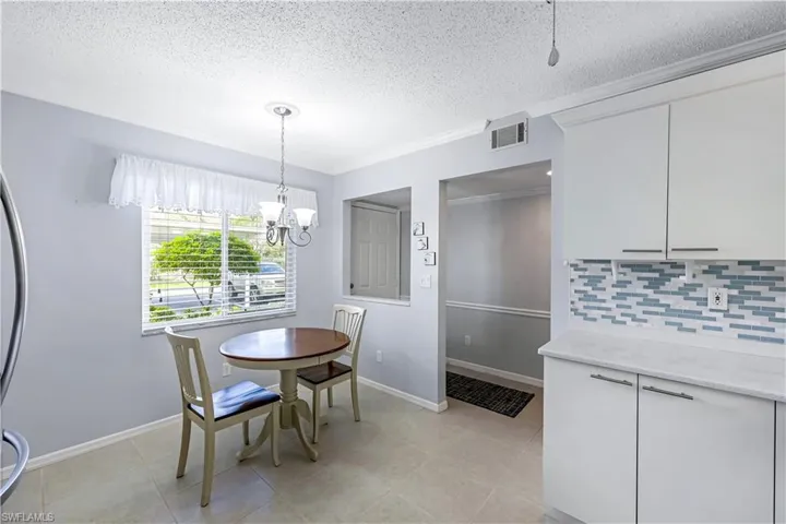 Dining area featuring a textured ceiling, a chandelier, light tile patterned flooring, and ornamental molding