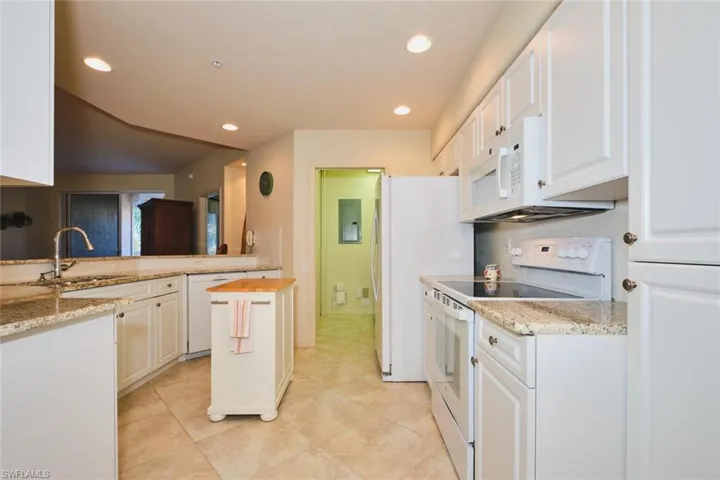 Kitchen with white appliances, recessed lighting, light stone countertops, white cabinets, and light tile patterned floors