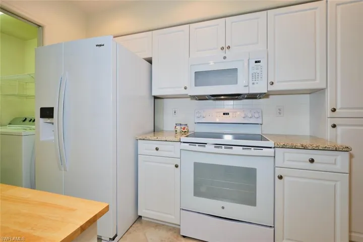 Kitchen featuring white appliances and white cabinets