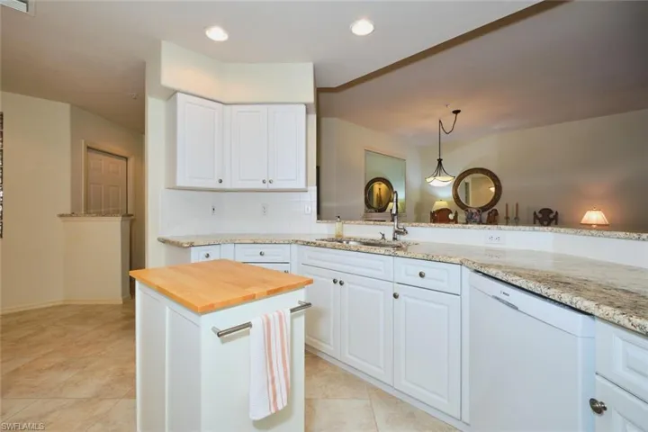 Kitchen with white dishwasher, light stone counters, white cabinetry, decorative backsplash, and recessed lighting
