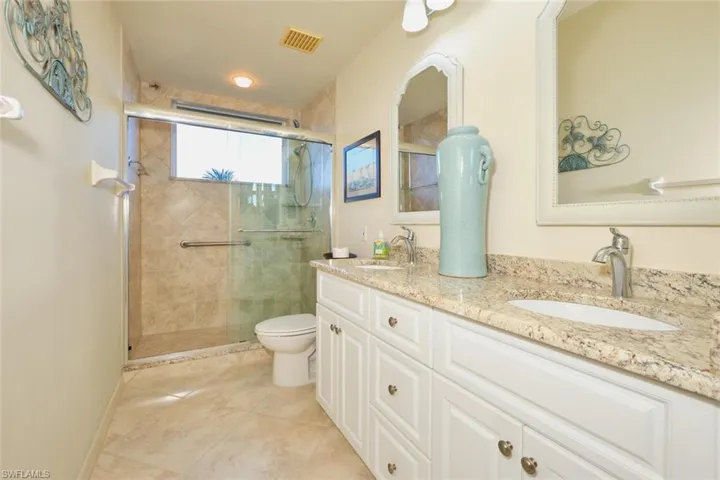 Full bathroom with double vanity, a stall shower, and light tile patterned floors