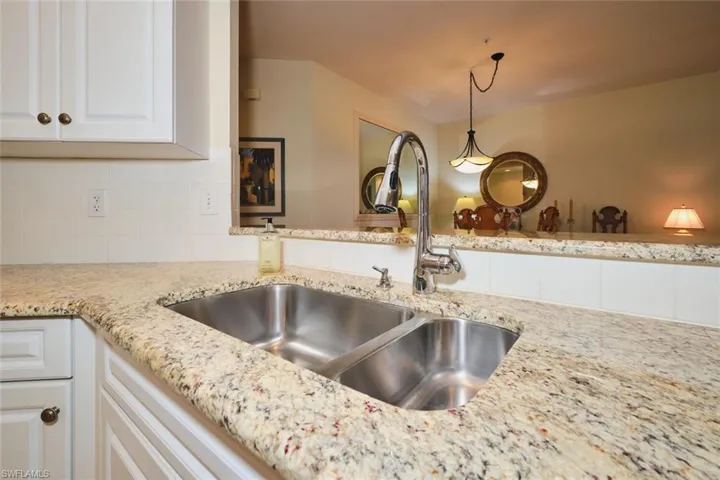Kitchen featuring light stone counters, white cabinetry, tasteful backsplash, and pendant lighting