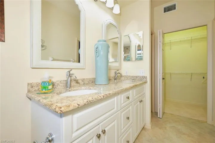 Full bath with double vanity, a spacious closet, and light tile patterned floors