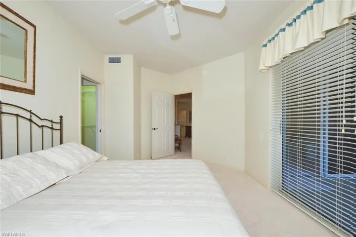 Carpeted bedroom with ceiling fan and a walk in closet