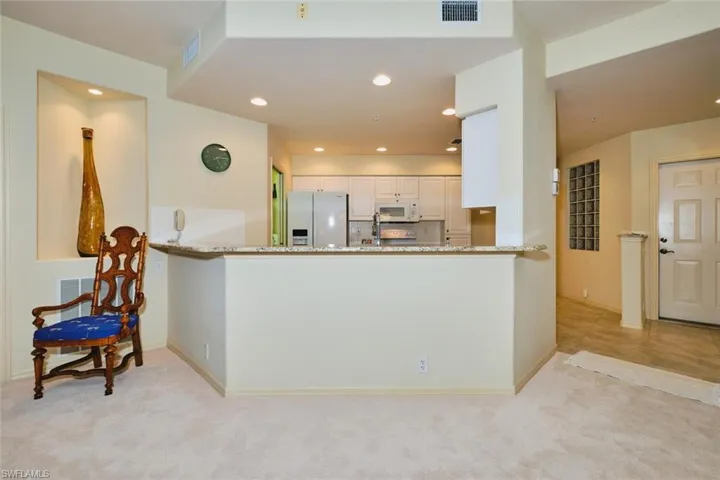 Kitchen with light stone countertops, white appliances, recessed lighting, backsplash, and white cabinets