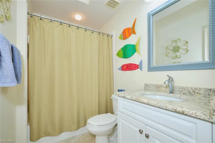 Bathroom featuring vanity, shower / bath combo, and light tile patterned flooring