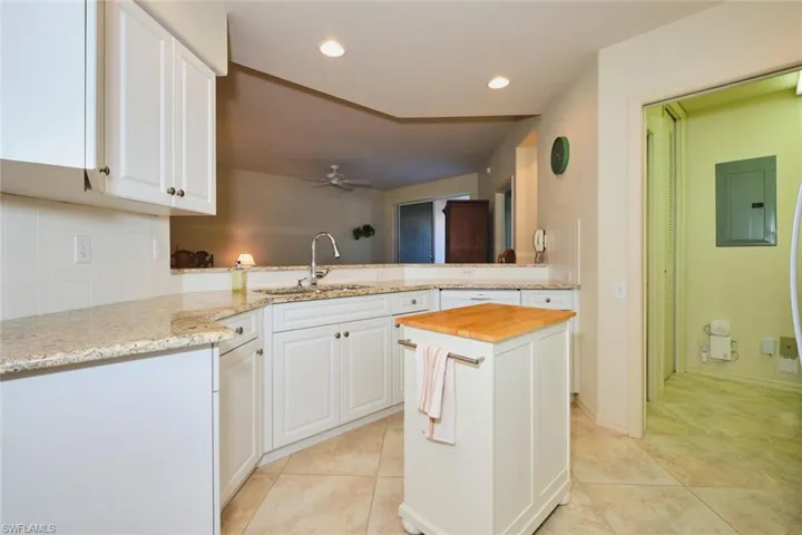 Kitchen featuring a peninsula, light stone countertops, white cabinetry, electric panel, and recessed lighting