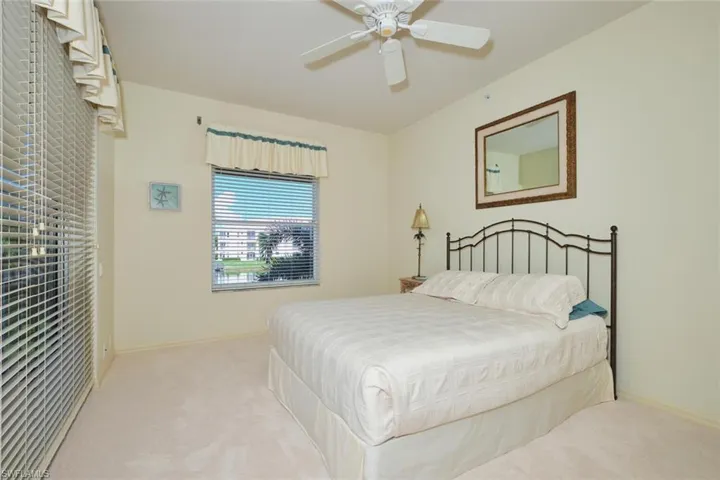 Carpeted bedroom with ceiling fan and baseboards