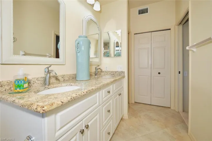 Full bathroom featuring double vanity, light tile patterned floors, and a closet
