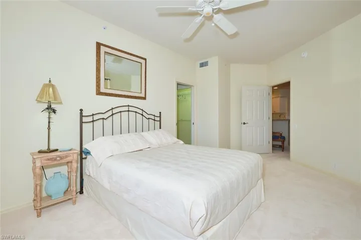 Carpeted bedroom with ceiling fan and a walk in closet