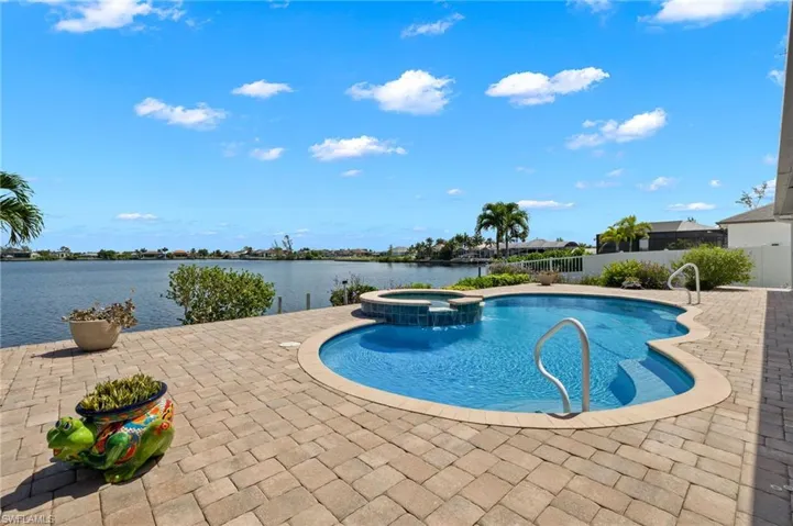 Large custom pool with spill over spa has a pavered deck with tons of room for lounge chairs.