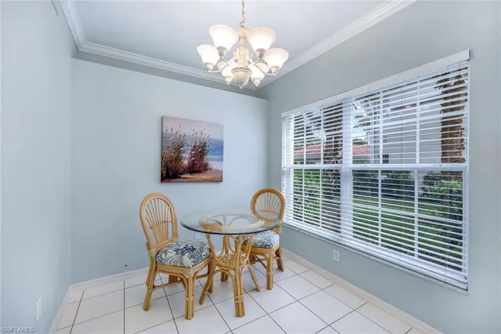 Tiled dining area with an inviting chandelier and ornamental molding