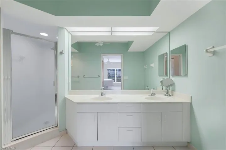 Bathroom featuring tile patterned flooring, vanity, ceiling fan, and a shower with shower door