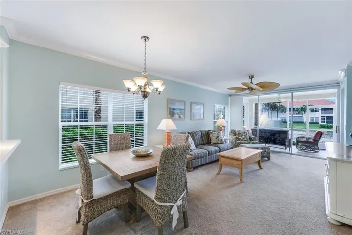 Dining area featuring ornamental molding, ceiling fan with notable chandelier, and light carpet