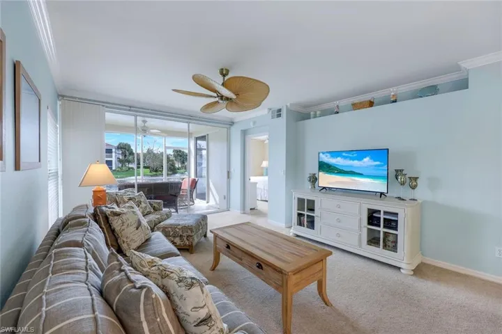 Living room featuring ornamental molding, light colored carpet, and ceiling fan