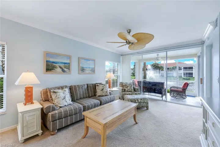 Living room featuring a wealth of natural light, light carpet, ceiling fan, and crown molding