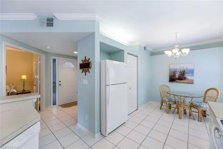 Kitchen with ornamental molding, a chandelier, light tile patterned floors, and white appliances