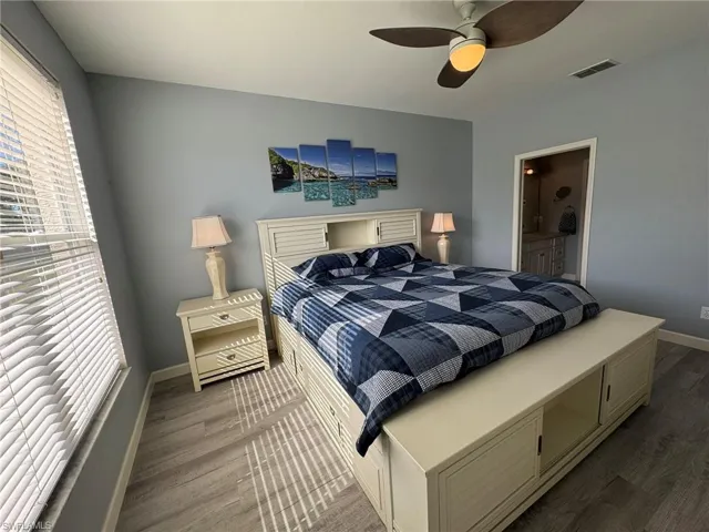 Bedroom with ceiling fan, hardwood / wood-style floors, and multiple windows