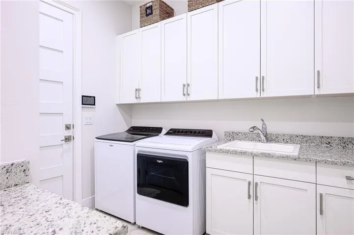 Extra Large Laundry area with cabinets, washing machine and clothes dryer, and sink