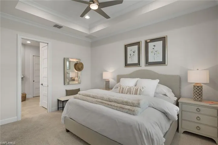 Primary Bedroom with a raised ceiling, crown molding, and light colored carpet