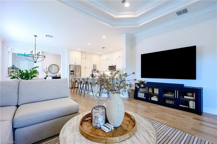 Living room featuring a notable chandelier, crown molding, and light hardwood / wood-style flooring