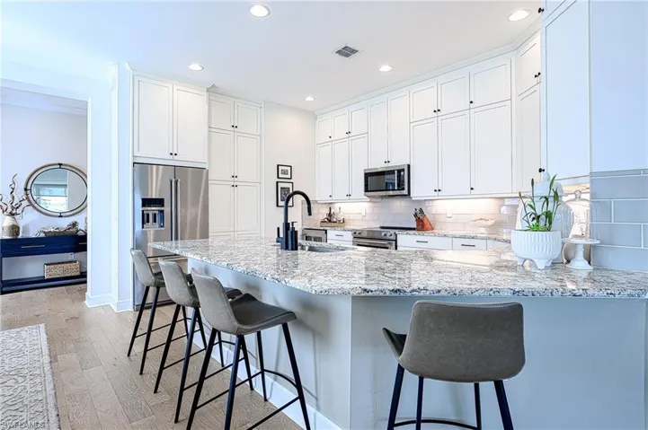 Kitchen with a breakfast bar, tasteful backsplash, white cabinetry, sink, and stainless steel appliances