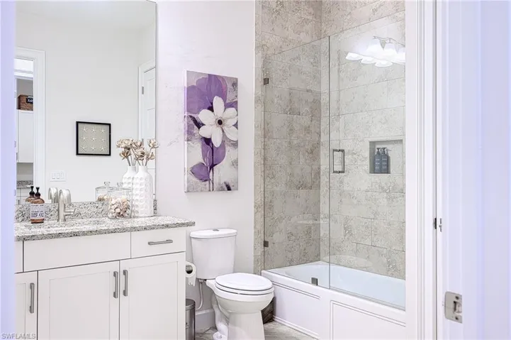 Guest Full bathroom featuring toilet, vanity, and bath / shower combo with glass door