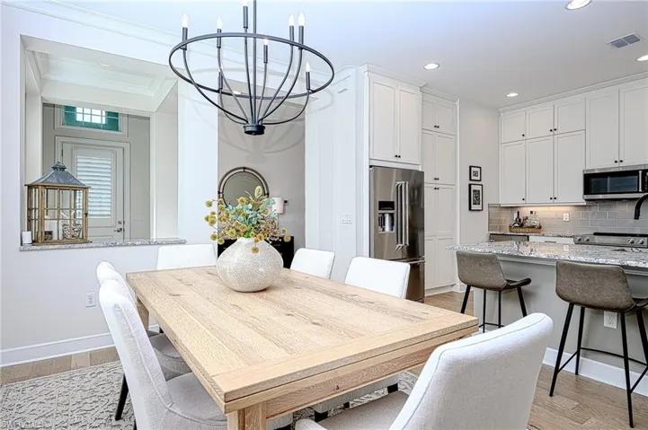 Dining area with an inviting chandelier, ornamental molding, and light hardwood / wood-style floors
