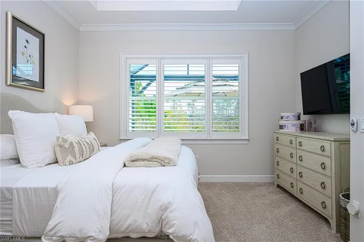 Primary Bedroom with crown molding and light colored carpet