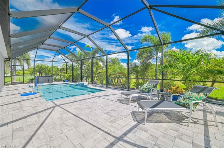 Outdoor pool with glass enclosure, a sunroom, and a patio