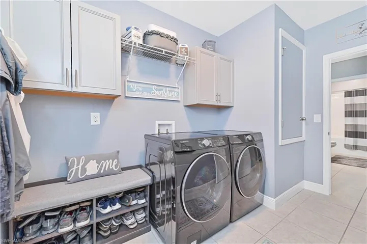 Laundry room featuring light tile patterned flooring, cabinet space, and washing machine and dryer
