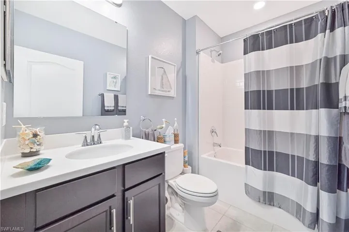 Full bath featuring shower / tub combo with curtain, vanity, and light tile patterned floors