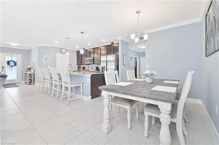 Dining room with ornamental molding, light tile patterned floors, a chandelier, and recessed lighting