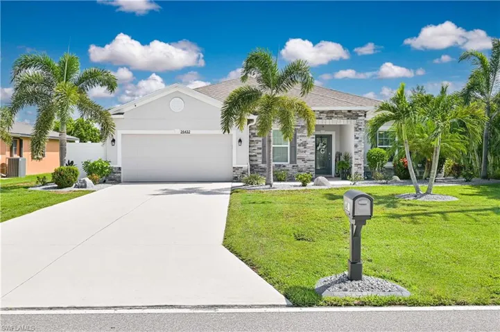 View of front of property featuring an attached garage, a front yard, stone siding, concrete driveway, and stucco siding