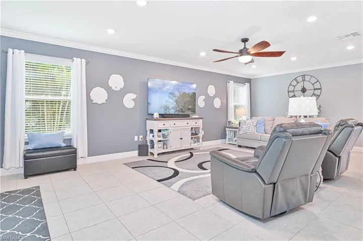 Living room featuring ornamental molding, light tile patterned floors, recessed lighting, and ceiling fan