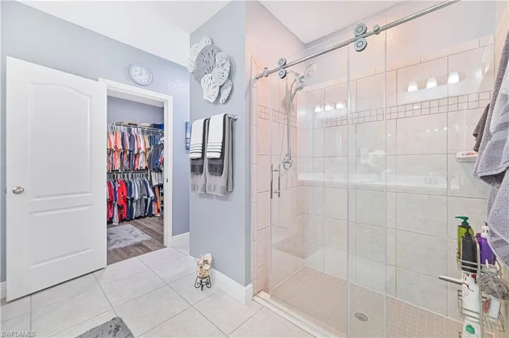 Bathroom featuring tile patterned flooring, a stall shower, and a spacious closet