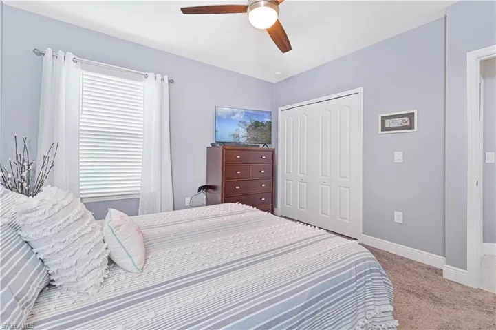 Bedroom with light carpet, ceiling fan, and a closet