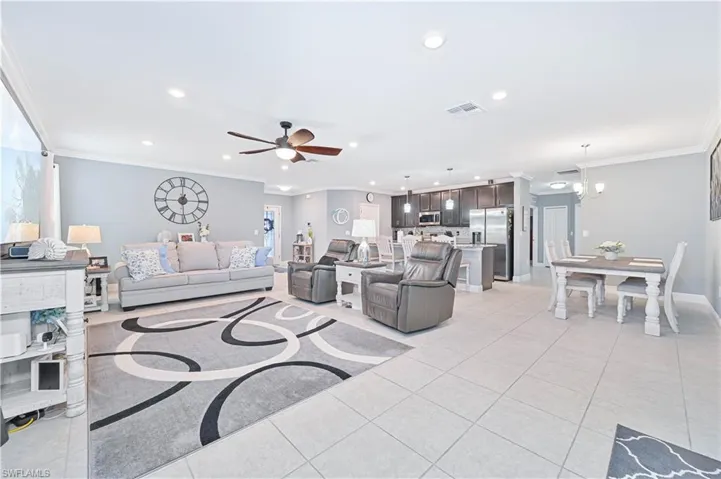 Living room with ornamental molding, light tile patterned floors, recessed lighting, a ceiling fan, and a chandelier