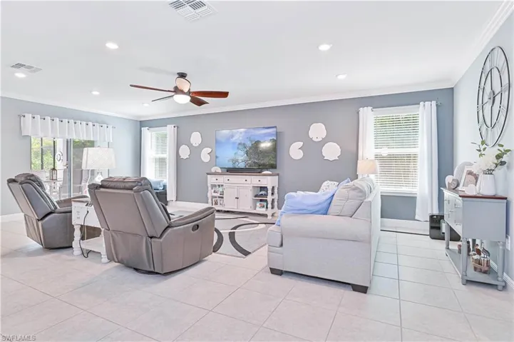 Living room featuring ornamental molding, light tile patterned floors, ceiling fan, and recessed lighting