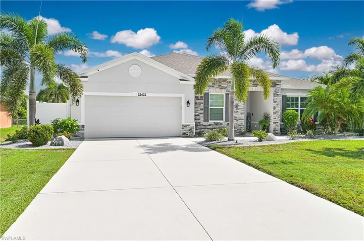 View of front of property with an attached garage, a front yard, stucco siding, and driveway