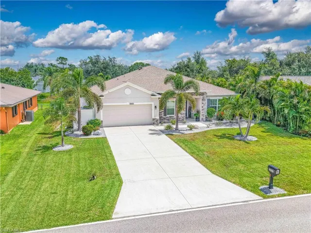 Single story home featuring a garage, driveway, a front lawn, stone siding, and stucco siding