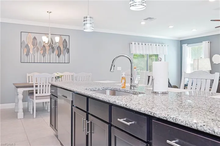 Kitchen with ornamental molding, light stone counters, pendant lighting, light tile patterned floors, and recessed lighting