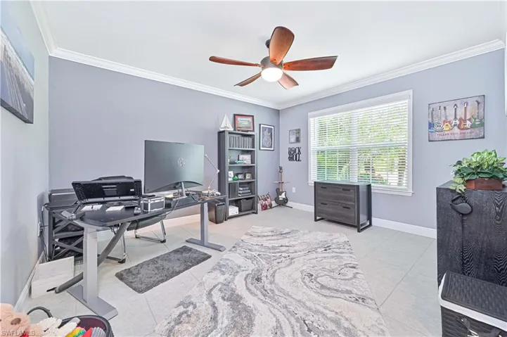 Office space with crown molding, light tile patterned floors, and a ceiling fan