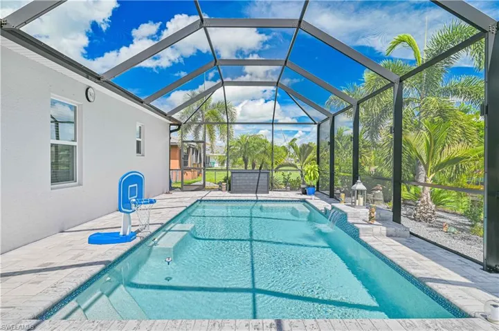 Swimming pool featuring a patio, a sunroom, and glass enclosure