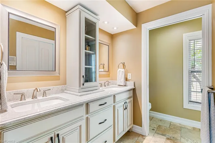Dual vanity featuring white cabinetry, undermount sinks, and light-toned countertops - Virtually Edited Image