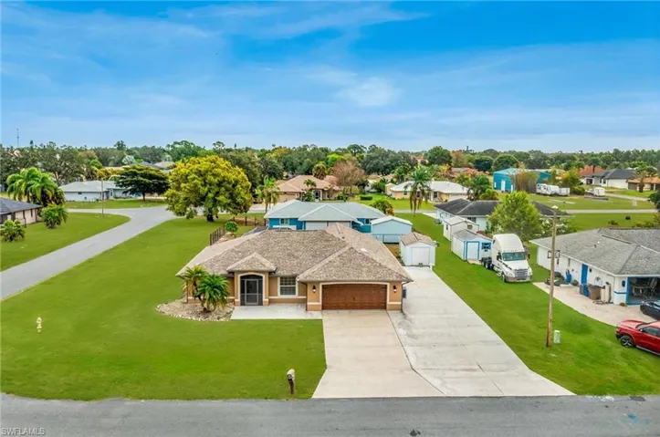 Single-story stucco residence featuring an attached two-car garage with a wood-finish door, a paved driveway, and a shingle roof - Virtually Edited Image