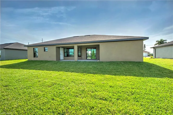 Rear view of property with a lawn and a patio area
